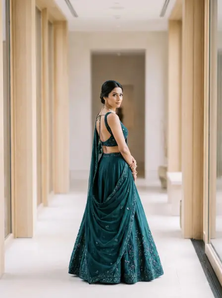 Indian bride wearing a dark green embroidered lehenga looking over her shoulder in a modern minimalist hallway.